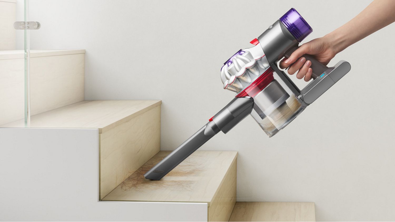 The Dyson Car+Boat handheld vacuum with the crevice tool cleaning a stair case.